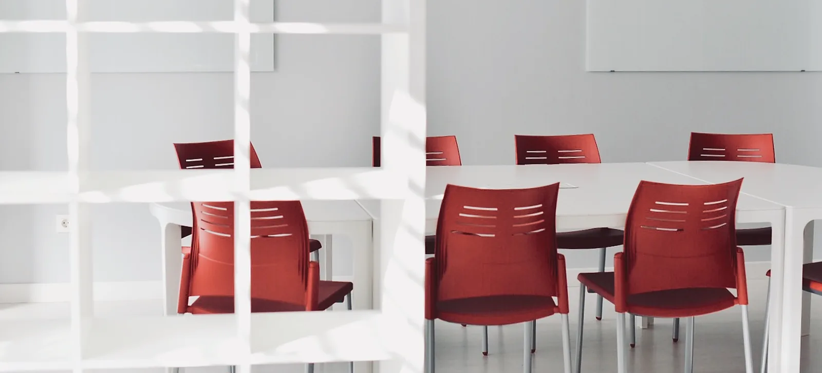 Aula con mesas blancas y sillas rojas