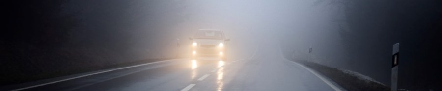 Dense fog on the country road, oncoming traffic